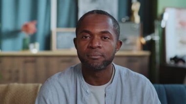 Kameraya bakıp gülümseyen iyi görünümlü Afro-Amerikan bir adamın görüntüsü. Çatı katında rahat gömlekli neşeli bir iş adamı. İçeride. Pozitif duygular