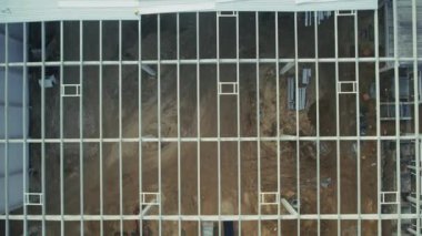 Bölgeyi aydınlatan mavi ışıkların yer aldığı ve yoğun, yenilikçi kentsel manzarayı vurgulayan, yukarıdan inşa halinde olan modern bir bina keşfedin.