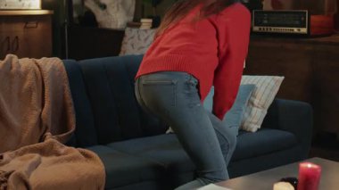 Videoda, rahat bir oturma odasında, kırmızı kazaklı, mavi koltuklu ve tabletiyle modern bir hayat süren bir kadının görüntüsü var.