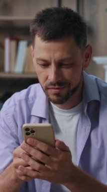 Açık mor gömlekli bir adam düşünceli bir şekilde oturur, samimi bir ortamda kişisel meseleleri düşünür..