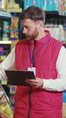 Adanmış ve odaklanmış bir medya stokçusu canlı bir perakende mağazası ortamında ürünleri özenle düzenler ve düzenler