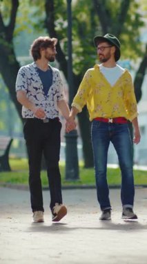 Neşeli bir çift, güneşli bir günde, güzel ve canlı bir parkta el ele dolaşır.