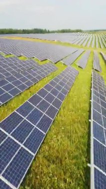 Çimenli bir alanda, sürdürülebilirlik için yenilenebilir enerjinin önemini vurgulayan güneş panellerinin panoramik bir görüntüsü