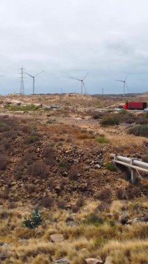 Bu video, tepenin üstünde rüzgar türbinleri olan, teknoloji ve doğayı harmanlayan, yenilenebilir enerji içeren sakin bir çöl manzarasını içeriyor.