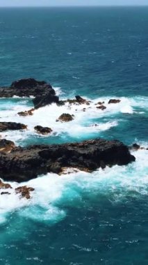 Bu büyüleyici video engin bir su kütlesinin dingin güzelliğini sergiliyor. Dalgalar engebeli kayalara çarpıyor, doğanın gücünü vurguluyor.