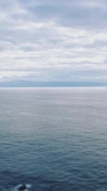 Arka planda bulutlu bir gökyüzü eşliğinde muazzam bir su boşluğu var. Bu da sakin bir atmosfer yaratıyor.