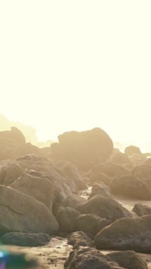 Sahil kenarındaki engebeli kayaların sakin bir sahnesi. Manevi aydınlatmayla daha da güzelleşiyor.