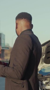 Terzi kıyafeti giymiş çok şık bir adam şehir ortamında akıllı telefonunu kontrol ediyor.