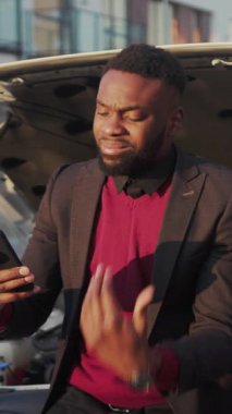 Takım elbiseli bir işadamı teknoloji dünyasında geziniyor. Telefonunu açık bir bagajda kontrol ediyor ve kırmızı bir kazak giyiyor.