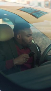 Modern bir ortamda, iyi giyimli bir adam beyaz bir arabanın yanında kurumsal bir hayat sürüyor, telefonuyla meşgul, aciliyet ve başarıyı yansıtıyor.