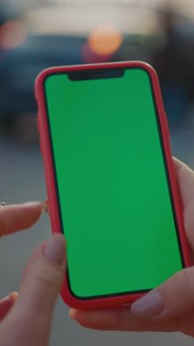 Yakın çekim görüntüsü, canlı yeşil ekranlı akıllı bir telefonu nazikçe tutan eller, kolay ve pürüzsüz düzenleme için mükemmel.