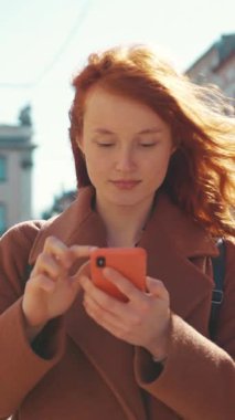 Bu video, telefonuna tepki veren kızıl saçlı bir kadını gösteriyor. Şaşkınlıkla başlıyor ve modern iletişimin heyecanını yansıtıyor.