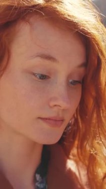 Bu büyüleyici videoda kızıl saçlı, kendine güvenini ve ifadesini vurgulayan kahverengi ceketli bir kadın var.