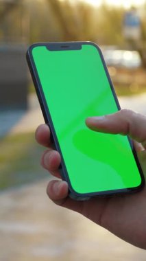 Bir el canlı yeşil bir ekran gösteren akıllı bir telefon tutuyor, ki bu medya projeleri ve modelleri için ideal.