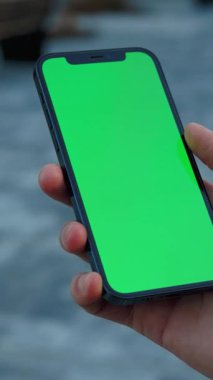 Uygulama demoları veya pazarlama görselleri yaratmak için ideal, canlı, yeşil bir ekran gösteren bir cep telefonu