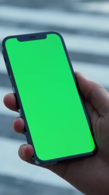 Açık bir el, canlı yeşil ekranlı, çeşitli medya projeleri için mükemmel parlak bir akıllı telefon tutuyor.