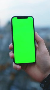 Kolayca kişiselleştirme ve yaratıcılık için canlı yeşil ekranlı şık bir akıllı telefon tutan bir kişi.