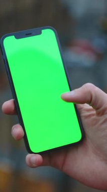 Düzenleme ya da kişiselleştirme için ideal canlı yeşil ekran gösteren akıllı telefonu sıkıca kavramış bir el.