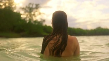 Huzurlu bir videoda sakin sularda bir kadın izleyiciyle bağlantı kuruyor. Güneş batarken, gölde zarafetle yüzüyor, özgürlüğü ve uyumu simgeliyor.