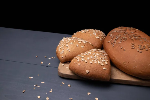 Siyah bir arka plan üzerinde çörekler ile bir tahta üzerinde Ekmek