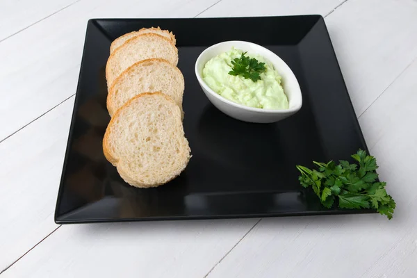 Ahşap arka planda beyaz kasede ekmek rulosu ile avokado sosu ve maydanoz yemeği fotoğrafı vejetaryenliği.