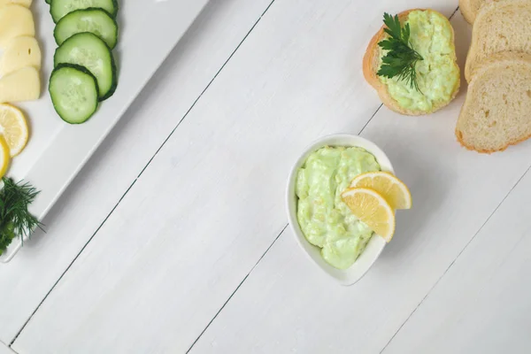 Ahşap arka planda salatalıklı avokado sosu düzgün yemek vejetaryenliği fotoğrafı.