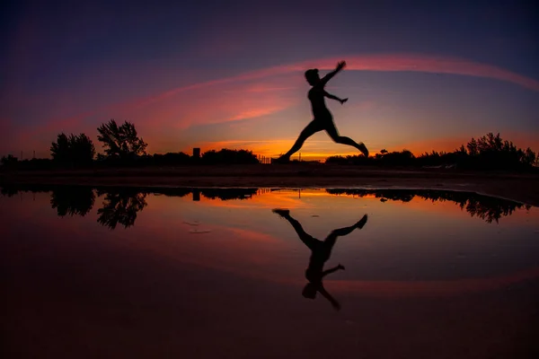 Vrouw Springen Het Strand Met Reflectie Het Water Bij Zonsondergang — Stockfoto