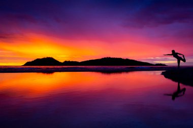 Yoga yapan kadın sahilde gün doğumunda poz veriyor