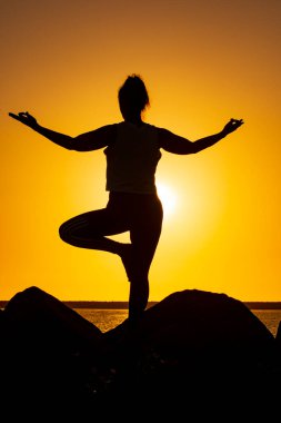 Gün batımında meditasyon yapan bir kadın silueti.