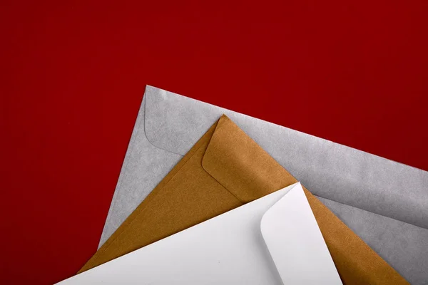 赤の背景に空の封筒の写真 アイデンティティをブランディングのテンプレートです 封筒のモックアップ 赤に分離されたホワイト ペーパー トップ ビュー — ストック写真