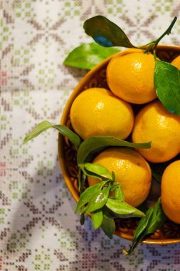 Mandalina (portakal, mandalina, clementines, narenciye) bir seramik tabak içinde yapraklarla
