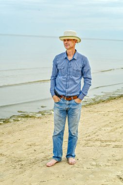 Denizin kenarında yürüyen bir adam.