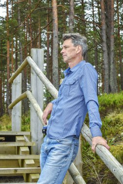 Ormanın içinde merdivenlerde oturan adam