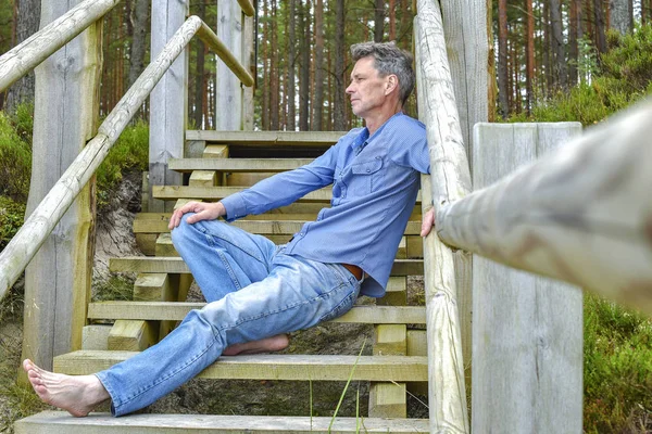 man resting on the stairs in the forest