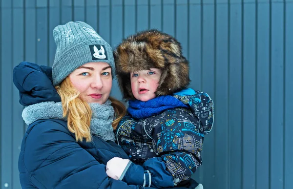 Junge Glückliche Frau Mit Sohn Arm Auf Blaugrauem Zaunhintergrund Winter — Stockfoto