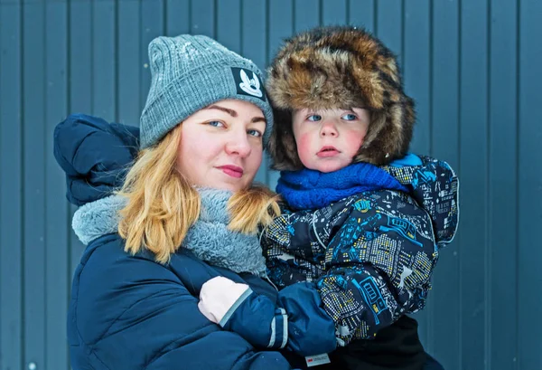 Junge Glückliche Frau Mit Sohn Arm Auf Blaugrauem Zaunhintergrund Winter — Stockfoto