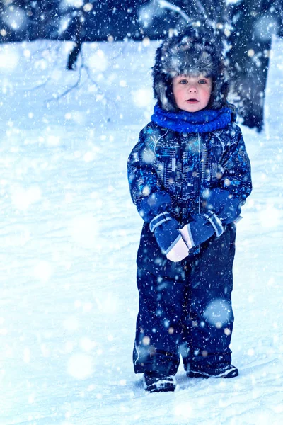 雪の中で屋外で遊んで全体と毛皮の帽子の服で面白い小さな男の子 寒い雪の日には冬の子供たちと積極的な休息 幸せな子供 — ストック写真