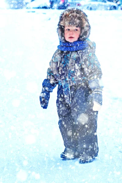 雪の中で屋外で遊んで全体と毛皮の帽子の服で面白い小さな男の子 寒い雪の日には冬の子供たちと積極的な休息 幸せな子供 — ストック写真