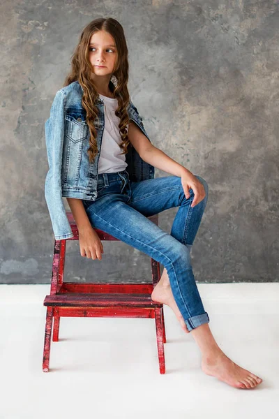 女孩模型坐在红色椅子上 灰色背景 — 图库照片