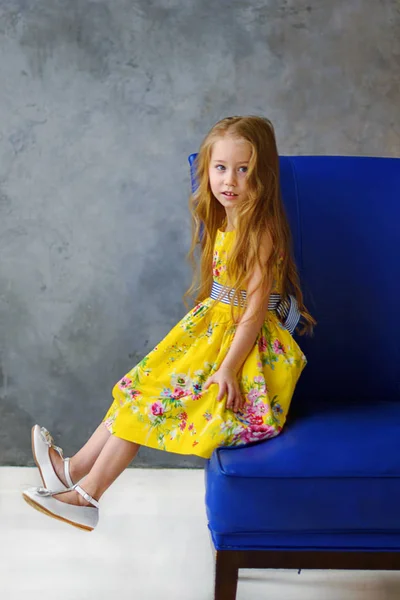 Portrait Cheerful Little Girl Bright Yellow Dress Blue Chair Bright — Stock Photo, Image