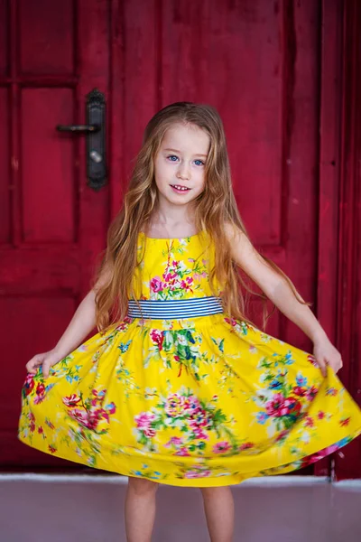 スタジオでポーズをとって黄色のドレスでかわいい女の子 スタイリッシュなロマンチックな夏の服装 ファッショナブルな明るい色 赤の背景 — ストック写真