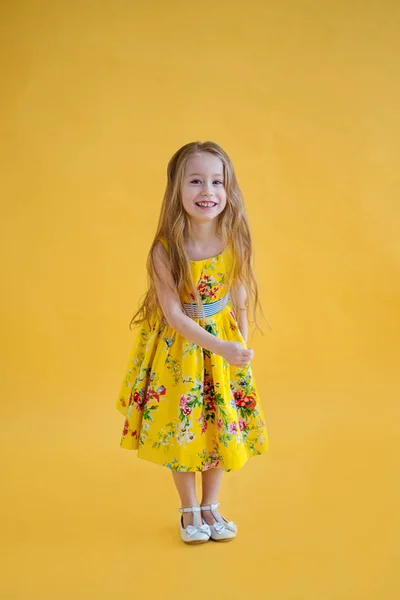 美しいドレスの色黄色背景に陽気なかわいい女の子 — ストック写真