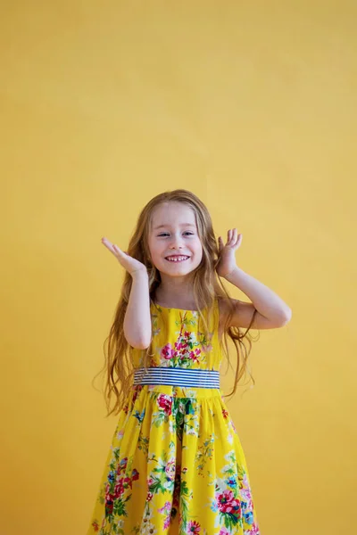 Vrolijke Schattig Meisje Een Mooie Jurk Een Gekleurde Gele Achtergrond — Stockfoto