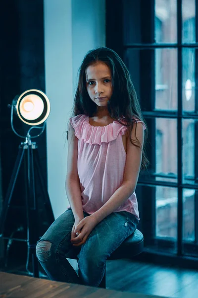 Cute girl in the Studio, the light from the lamp in the background.