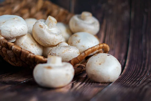 Champignonsfresh grzyby w koszu na podłoże drewniane. — Zdjęcie stockowe