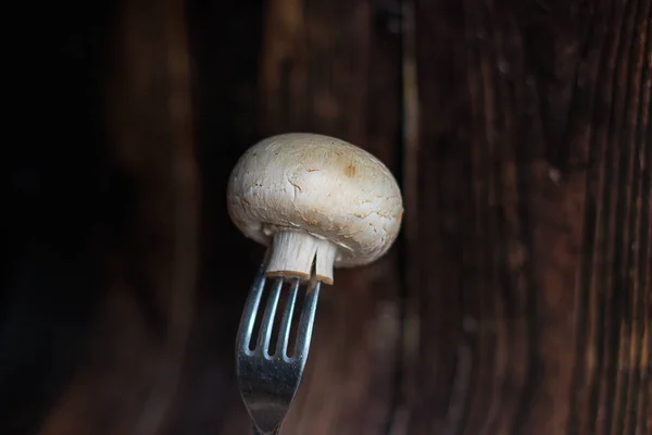 Čerstvé houby na vidličce na dřevěném pozadí — Stock fotografie