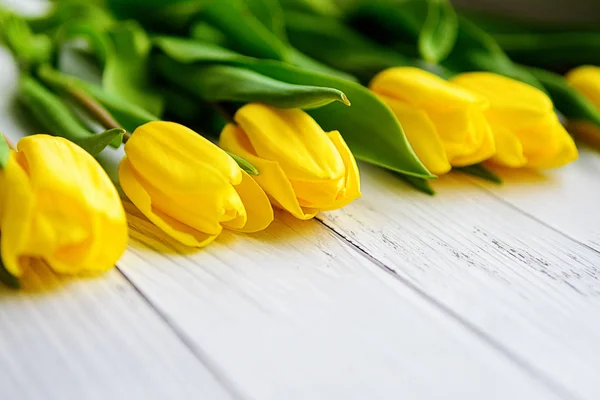 Amarelo tulipas flores sobre fundo de madeira branca. À espera da Primavera. Feliz Dia das Mães, 8 de Março. Posição plana, vista superior. Lugar para texto . — Fotografia de Stock