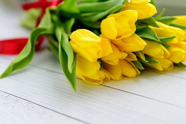 Buquê de flores de tulipas amarelas em fundo de madeira branca. À espera da Primavera. Feliz cartão de Páscoa, dia da mãe, 8 de Março. Posição plana, vista superior . — Fotografia de Stock