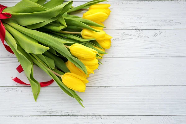 Buquê de flores de tulipas amarelas em fundo de madeira branca. À espera da Primavera. Feliz cartão de Páscoa, dia da mãe, 8 de Março. Posição plana, vista superior . — Fotografia de Stock