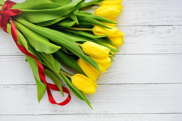 Buquê de flores de tulipas amarelas em fundo de madeira branca. À espera da Primavera. Feliz cartão de Páscoa, dia da mãe, 8 de Março. Posição plana, vista superior . — Fotografia de Stock